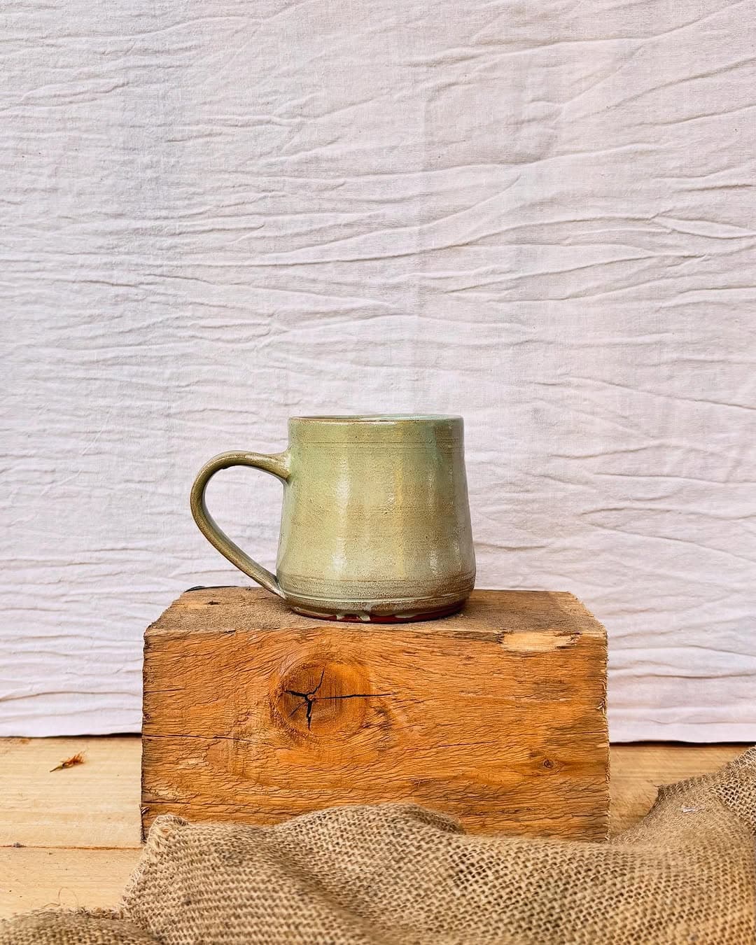 A wheel-thrown Studio Sira mug in a muted olive glaze